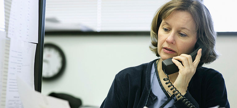 Businesswoman Using Telephone and Reading Paperwork 