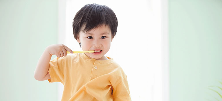 Young boy sitting and brushing teeth